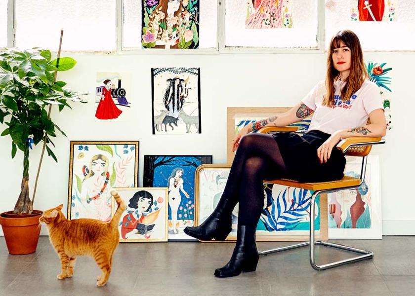 María Hesse poses with some of her illustrations and one of her cats. 