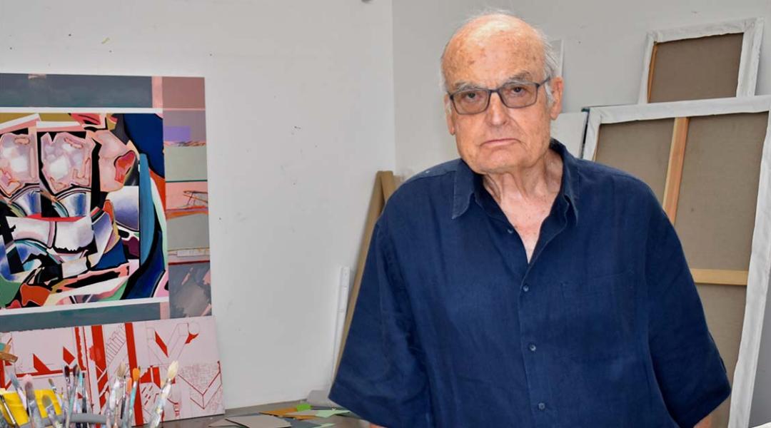 Veteran artist Luis Gordillo poses surrounded by paintbrushes and materials at his studio