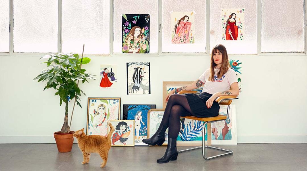 María Hesse poses with some of her illustrations and one of her cats. 