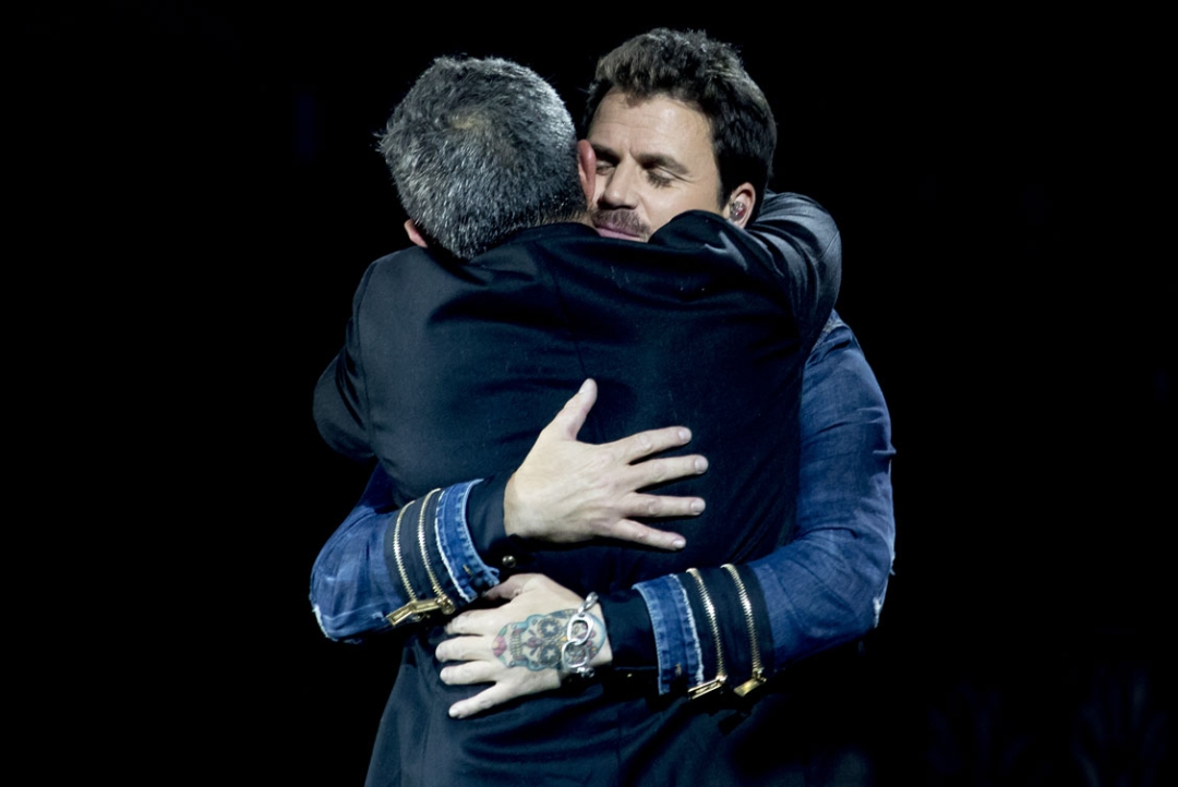 Alejandro Sanz and Dani Martín hug onstage during a concert